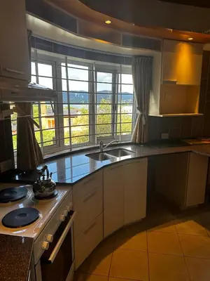 a kitchen with white cabinets and a sink and windows at La Serena in Villa Carlos Paz