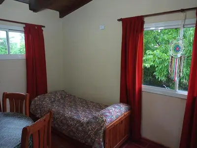 a bedroom with a bed and a window with red curtains at Estacion Potrero cabaña chica in Potrero de Garay