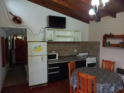 a small kitchen with a white refrigerator and a table at Estacion Potrero cabaña chica in Potrero de Garay