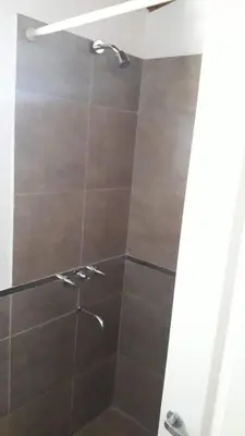 a bathroom with a shower with brown tile at Estacion Potrero cabaña chica in Potrero de Garay
