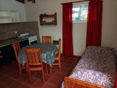 a kitchen with a table and chairs and a table and a bed at Estacion Potrero cabaña chica in Potrero de Garay