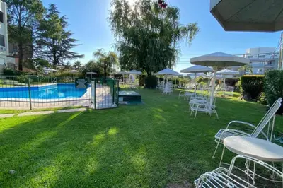 a yard with white chairs and a swimming pool at Departamento Villa Carlos Paz in Villa Carlos Paz