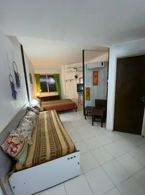 a room with two beds and a living room at Departamento Villa Carlos Paz in Villa Carlos Paz