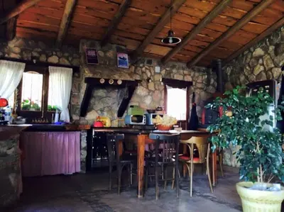 a kitchen with tables and chairs and a stone wall at Casa de ensueño in Villa Carlos Paz
