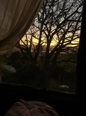 a sunset seen through a window with a tree at Casa de ensueño in Villa Carlos Paz