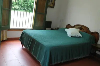 a bedroom with a bed with a green blanket and a window at Las Magnolias 4 dormitorios in Merlo