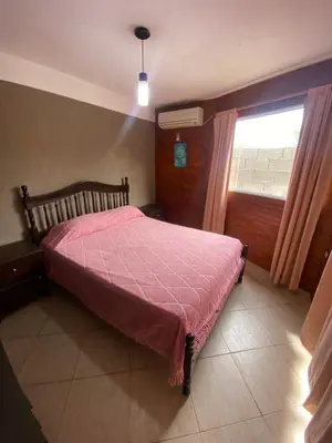 a bedroom with a bed with a pink comforter and a window at alquiler temporario en Mina Clavero in Mina Clavero