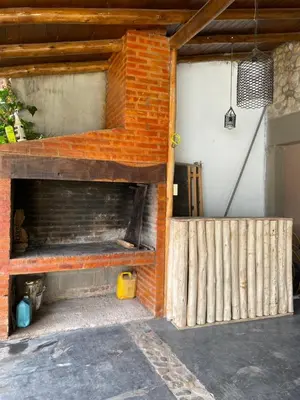 a brick fireplace in a garage with a wooden fence at alquiler temporario en Mina Clavero in Mina Clavero