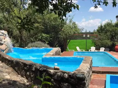 a pool in a yard with a stone retaining wall at Auken Penkoken in Merlo