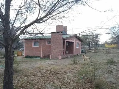 a dog running in front of a brick house at Casa con gran jardín a 100 mts del Río Amboy in Villa Amancay