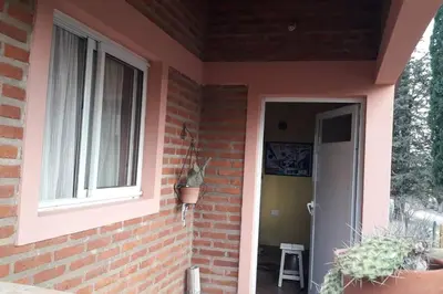 a pink brick house with a window and a door at Casa con gran jardín a 100 mts del Río Amboy in Villa Amancay