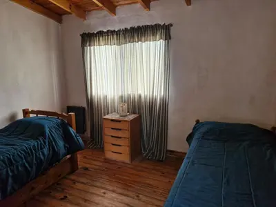 a bedroom with two beds and a dresser and a window at Lo de Juan in Villa General Belgrano