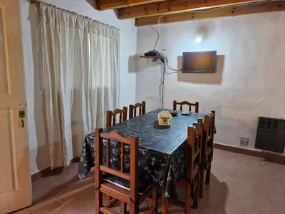 a dining room with a table and chairs and a television at Lo de Juan in Villa General Belgrano