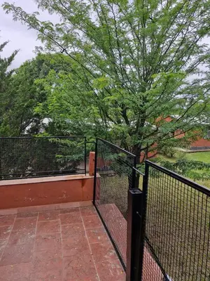 a balcony with a black fence and a tree at Lo de Juan in Villa General Belgrano