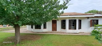 a small white house with a tree in the yard at Casa de campo EL LULI in La Bolsa