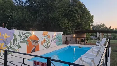 a swimming pool with two chairs next to a mural at Complejo NONA RITA in Villa Cura Brochero