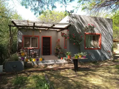a small house with a red door and a patio at Casa con piscina en entorno muy verde in Villa Anizacate