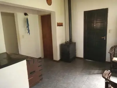 a living room with a black door and a kitchen at Casa con piscina en entorno muy verde in Villa Anizacate