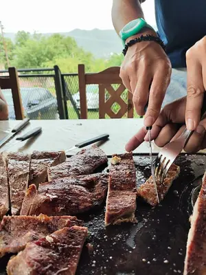a person is cooking meat on a grill at Casa REFUGIO PUNILLA in Cordoba