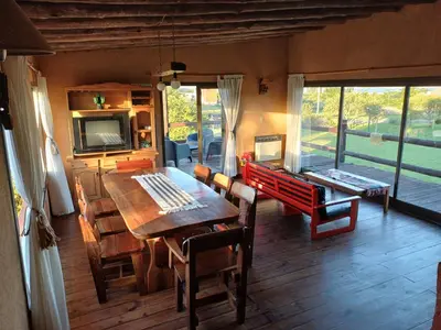 a dining room with a table and chairs and a television at Cabaña Espejo de Luna in La Estancia