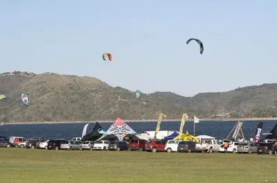 a row of cars parked next to the water with kites at Cabaña Espejo de Luna in La Estancia
