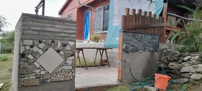 a house with a stone wall next to a patio at Cabaña LA LUGARDA in Cuesta Blanca
