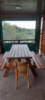 a wooden picnic table and a wooden chair in front of a window at Cabaña LA LUGARDA in Cuesta Blanca