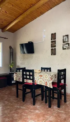 a dining room table with chairs and a tv on a wall at Cabañas Aires de montaña in Cordoba