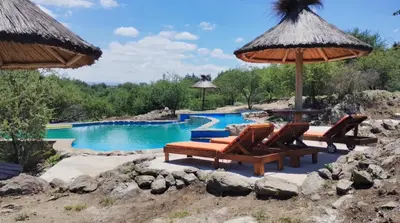 a pool with chairs and an umbrella and a swimming pool at Cabañas Aires de montaña in Cordoba