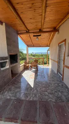 an outdoor patio with a wooden ceiling and a table at Cabañas Aires de montaña in Cordoba