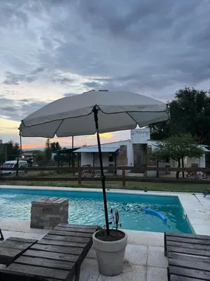 a large white umbrella sitting next to a swimming pool at Cabañas Los Mellis in Barrio Parque El Corcovado