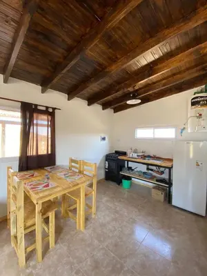 a kitchen with a wooden table and a refrigerator at Cabañas Los Mellis in Barrio Parque El Corcovado