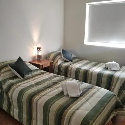 two twin beds in a room with a table at Viejo Camino Real in Santa Rosa de Calamuchita