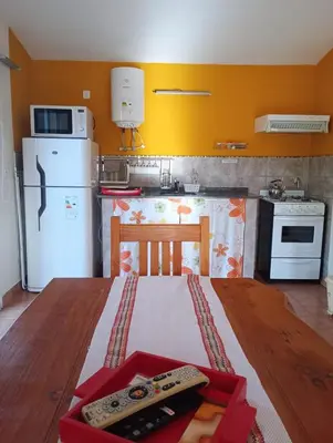 a kitchen with a table and a white refrigerator at Viejo Camino Real in Santa Rosa de Calamuchita