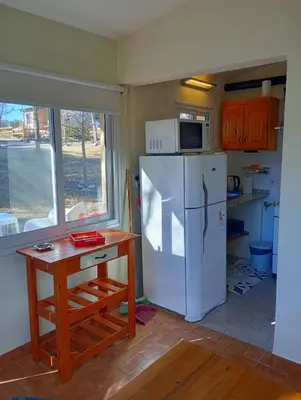 a kitchen with a white refrigerator and a table at Viejo Camino Real in Santa Rosa de Calamuchita