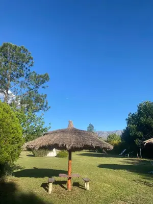a bench under an umbrella in a field at Complejo de cabañas en Nono in Nono