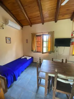 a bedroom with a bed and a table and a tv at Complejo de cabañas en Nono in Nono