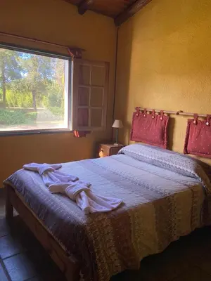 a bedroom with a large bed with a window at Complejo de cabañas en Nono in Nono
