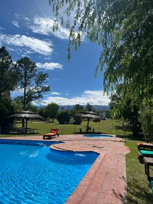 a swimming pool with benches and picnic tables in a park at Complejo de cabañas en Nono in Nono