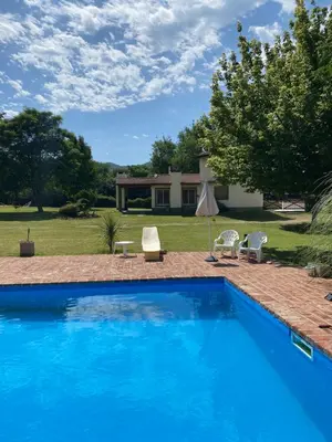a blue swimming pool with two chairs and a house at San Roque in San Roque