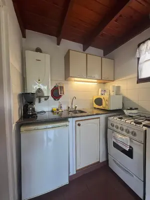 a kitchen with white cabinets and a sink and a stove at Cabañas Cerro Cristal in La Cumbrecita