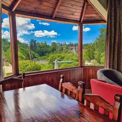 a room with a table and chairs and a large window at Cabañas Cerro Cristal in La Cumbrecita