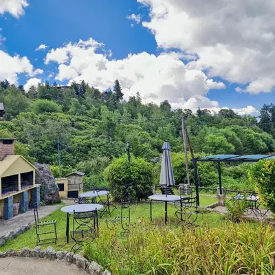 a group of tables and an umbrella in a field at Cabañas Cerro Cristal in La Cumbrecita