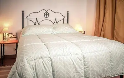 a bedroom with a bed with a white comforter at Cabañas Cerro Cristal in La Cumbrecita