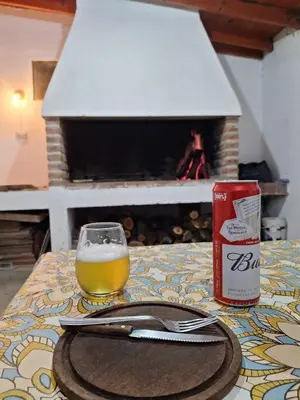 a glass of beer and a can on a table with a fireplace at Rancho La Paz in Los Reartes