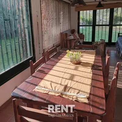 a wooden table in a room with chairs and windows at 