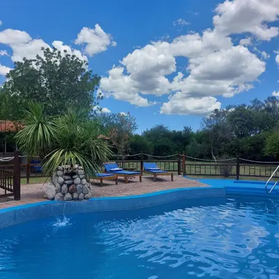 a swimming pool with two benches and a blue sky with clouds at Pasión Serrana in Las Calles
