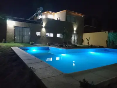 a swimming pool in front of a house at night at Dúplex, Alejandría in Villa Carlos Paz