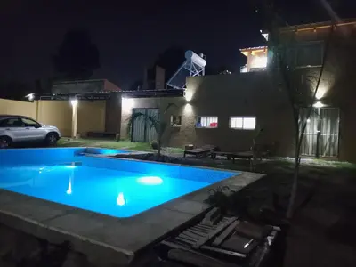 a swimming pool in front of a house at night at Dúplex, Alejandría in Villa Carlos Paz