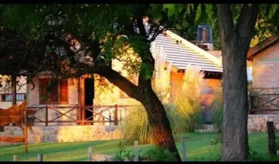 a house with a tree in front of it at Cabañas Raices in Mina Clavero